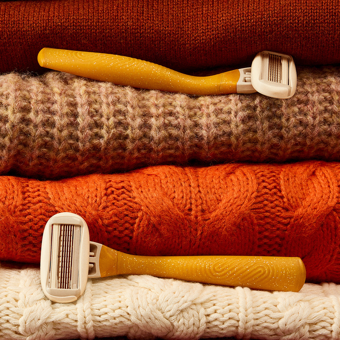Gold leaf Original Razor handles nestled in a stack of autumnal sweaters.