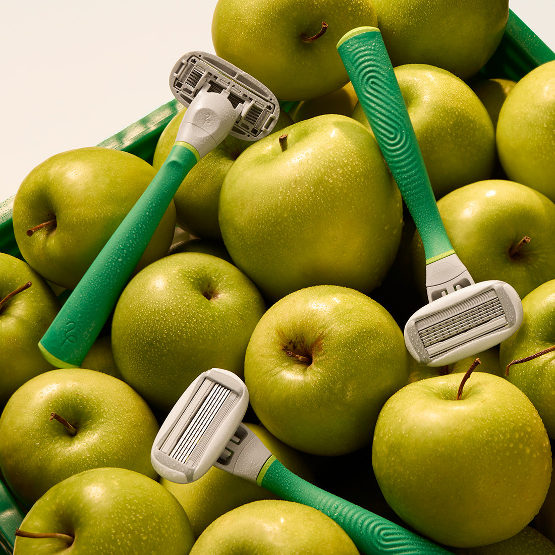Green razors atop a pile of green apples.