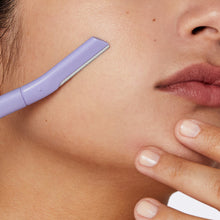 Person using the dermaplane on their cheek.