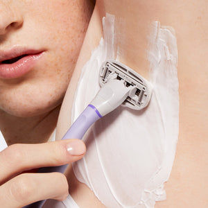 Close up of a person using the 
Lilac Original Razor and shave gel to shave their underarm.