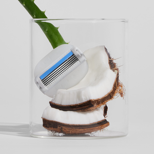 Moisture Plus blade in a clear glass jar with bits of fresh coconut and aloe.