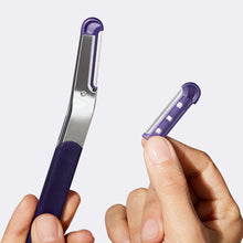 Close up of a woman's hands holding the dark purple and polished chrome Flamingo Refillable Dermaplane Razor with a refill blade in the other hand