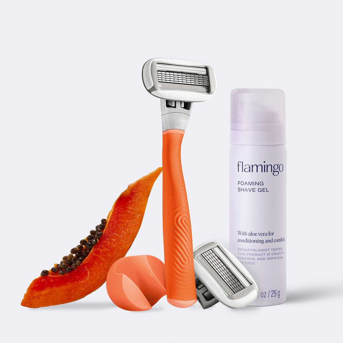 Orange razor with a half-cut papaya and a bottle of flamingo foaming shave gel on a white background