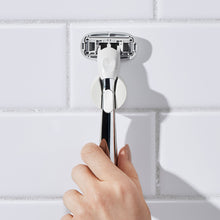 Hand placing the Chrome Razor back into its shower holder.