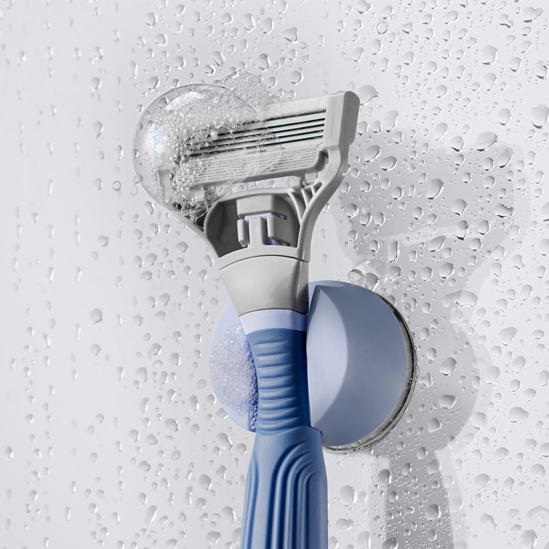 Pubic Razor in its shower holder with bubbles on the blade.