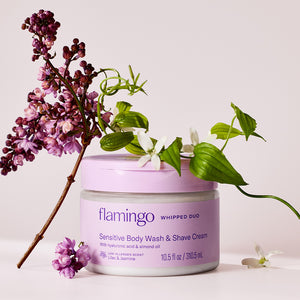 Jar of the Whipped Duo with sprigs of lilac and jasmine on a beige background.