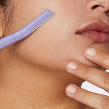 Close up of a woman using a Flamingo Disposable Dermaplane Razor on her cheek