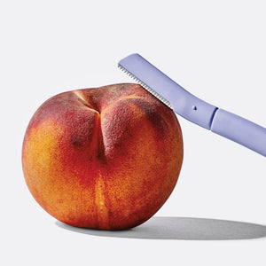 Flamingo Disposable Dermaplane Razor balanced on a ripe peach