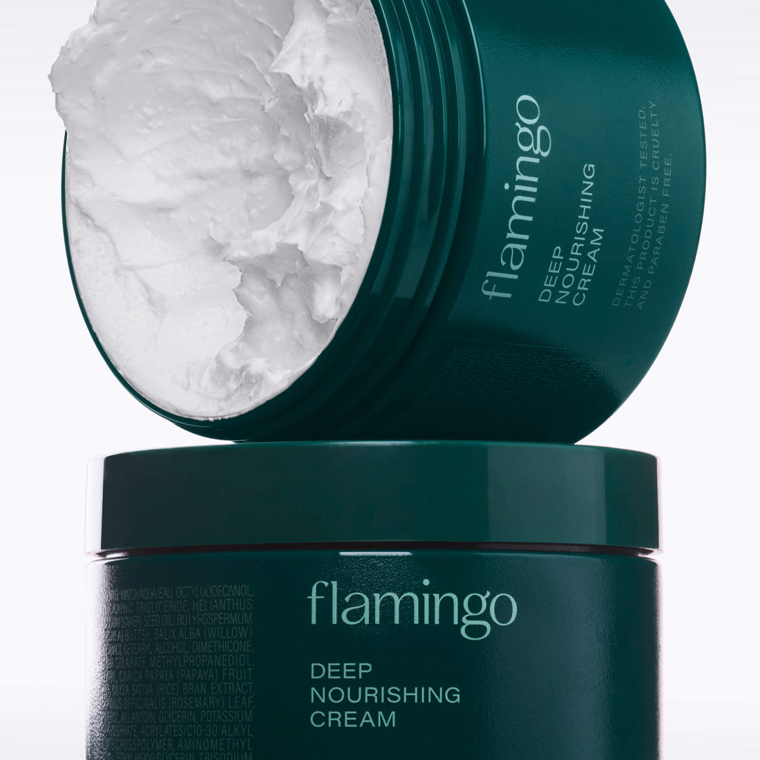 A dark green, open jar of Flamingo Deep Nourishing Cream showing the whipped texture balanced on top of a closed jar