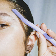 Close up of a woman using a lilac Flamingo Disposable Dermaplane razor to shape her eyebrow