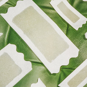 Different sized Flamingo Wax strips on a green leather background
