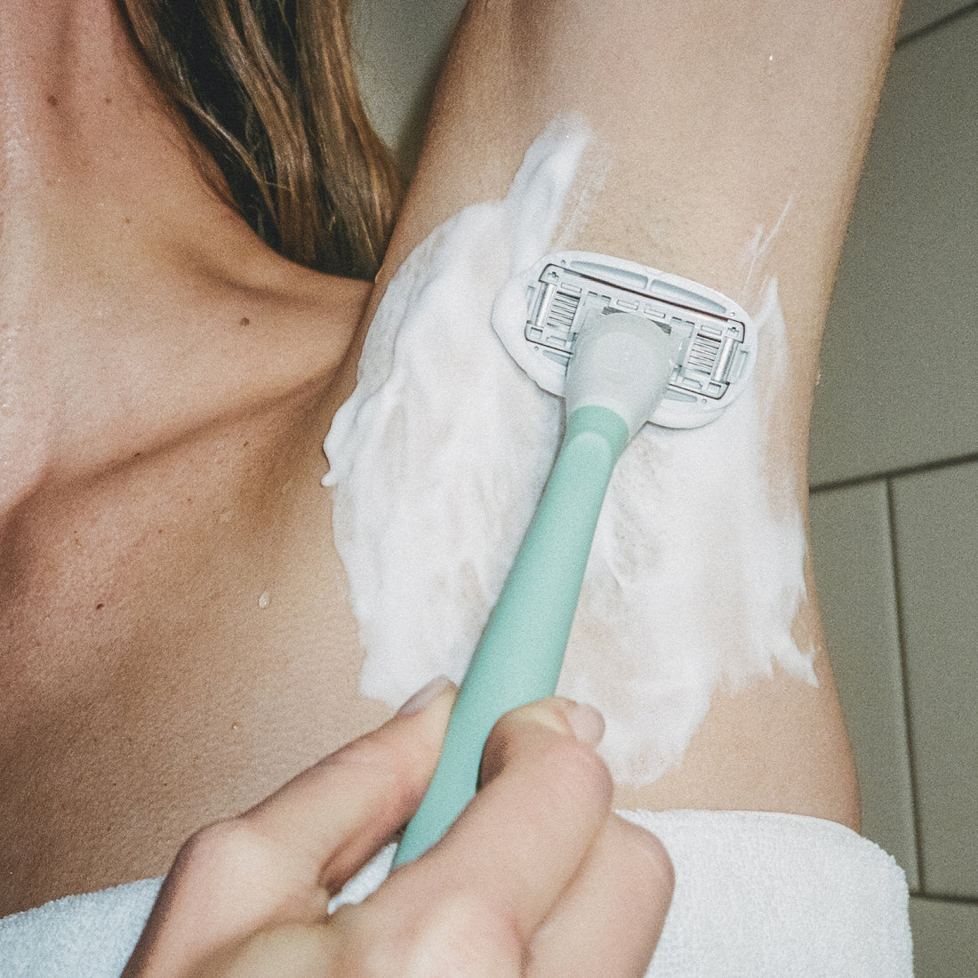 Woman in the shower shaving her shave gel covered armpit area with the Sage Flamingo razor