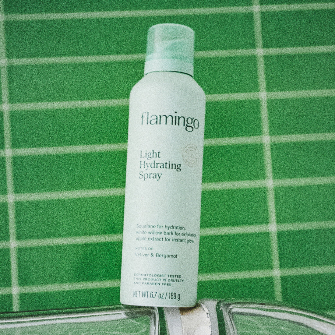 Pale green can of Flamingo Light Hydrating Spray in a bright green tiled bathroom
