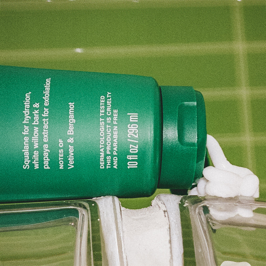 Open, green tube of Flamingo Daily Moisturizing Lotion in a bright green tiled bathroom