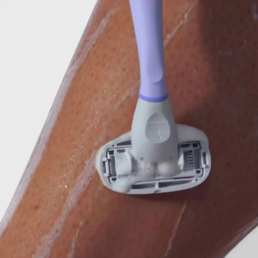 Person using the Lilac Original Razor and the Nourishing Shave Oil to shave their shin.