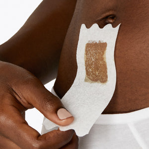 Closeup of a woman in white cotton underwear with a small wax strip on the area below her bellybutton