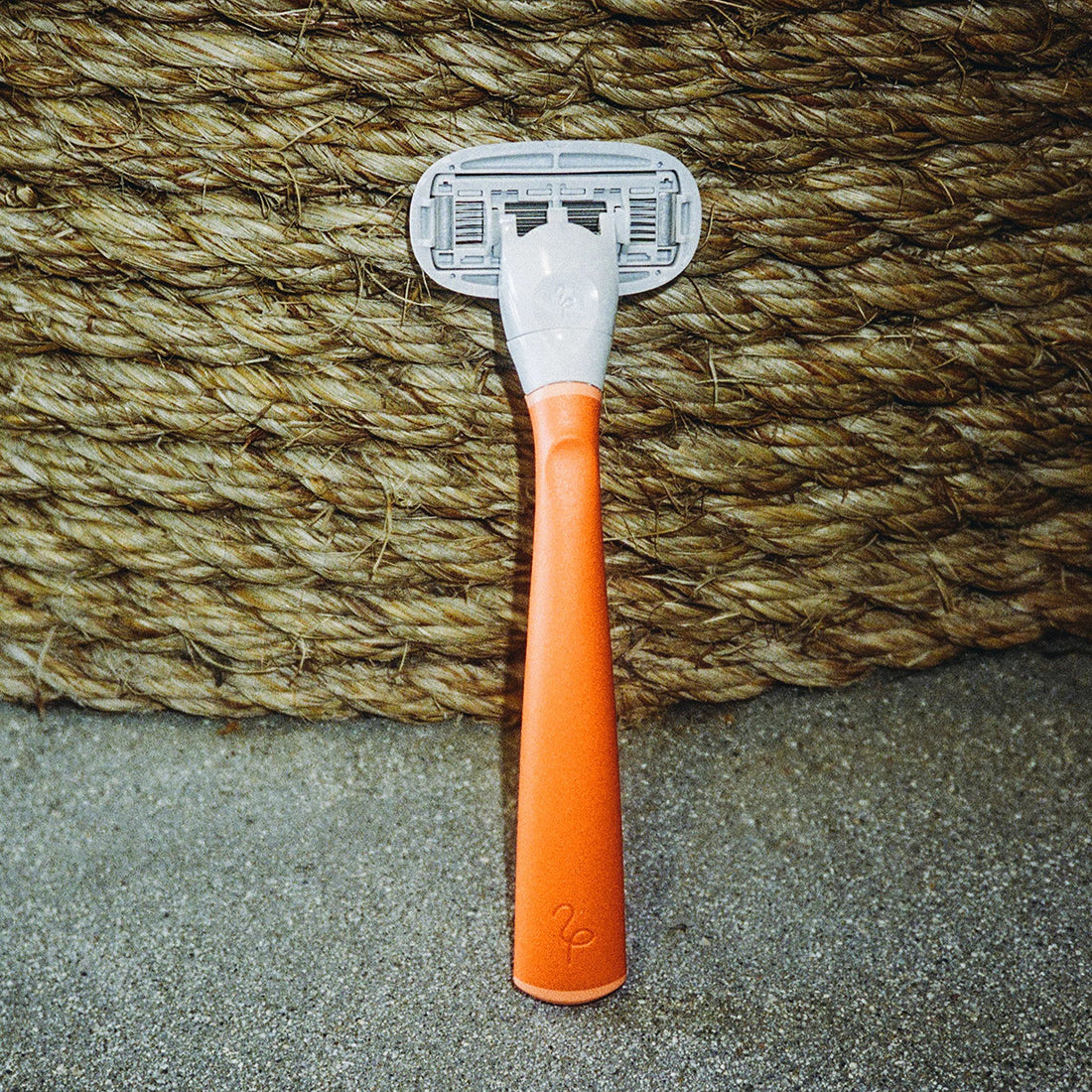 Product shot of the Flamingo Razor in Papaya with a jute rope coil in the background