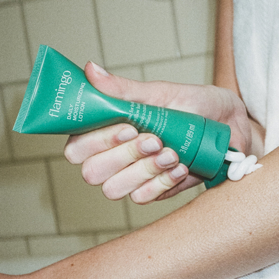 Woman squeezing Flamingo lotion onto her forearm