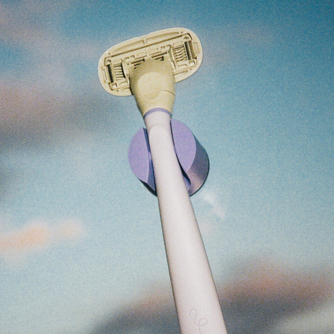 Flamingo Razor in the color Lilac in the matching shower holder with a gradient sky background